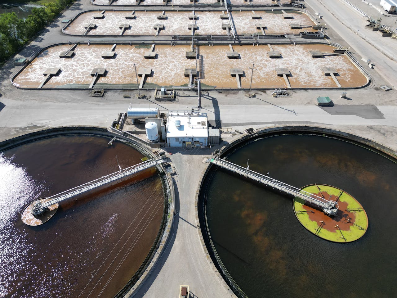 Aerial shot of an industrial water treatment plant with large circular tanks.