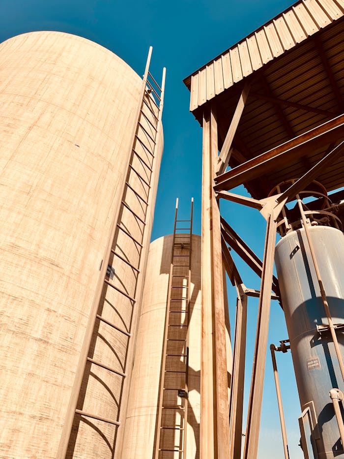 Close-up of large water treatment tanks with ladders against a clear blue sky.